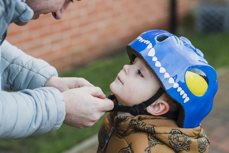 A father fastens his son's safety helmet before going out to play.