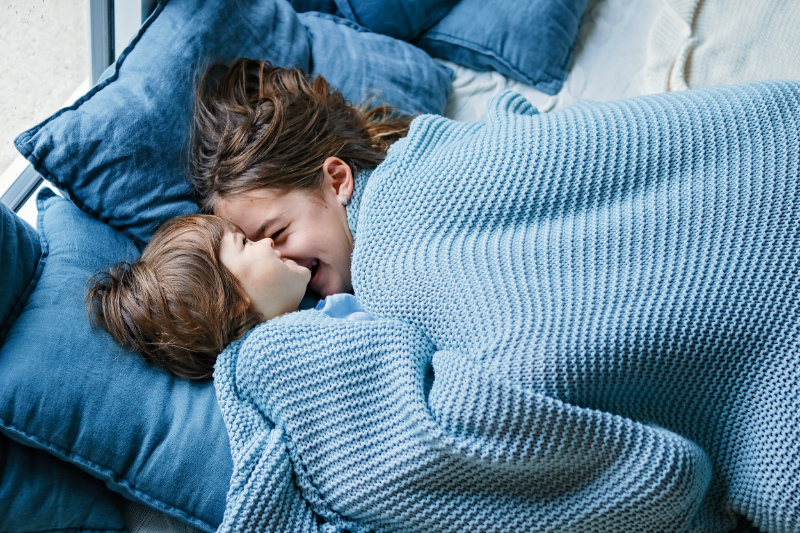 What Is Radon and Why Is It Bad? Siblings snuggling under covers in a bed.